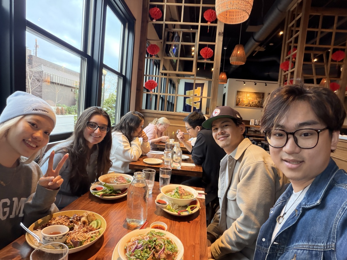 The four teammates at dinner, leaning into one photo over bowls of food.
